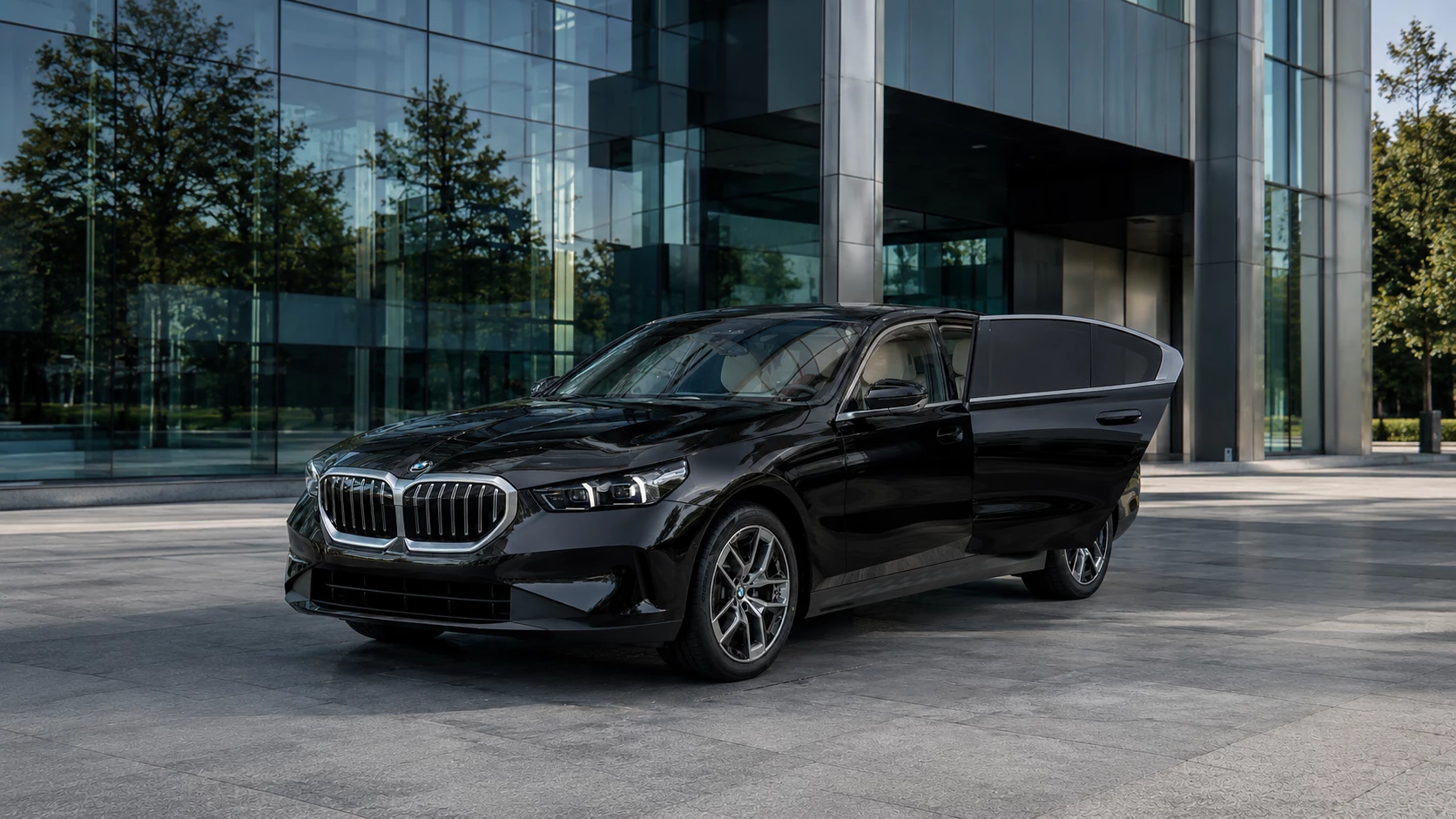 Black executive saloon with rear passenger door open outside a modern office